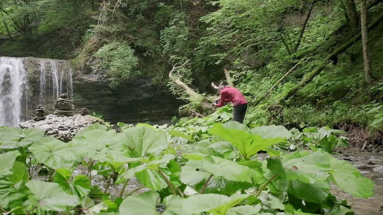 Photographer wearing a red jumper walks around trying to find a compositon for the waterfall