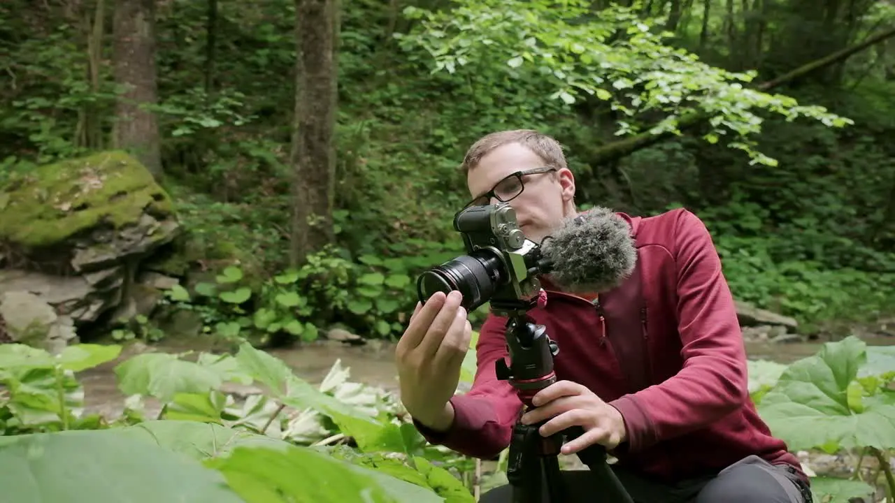 Photographer putting a filter on the front of his lens photographing green leaves