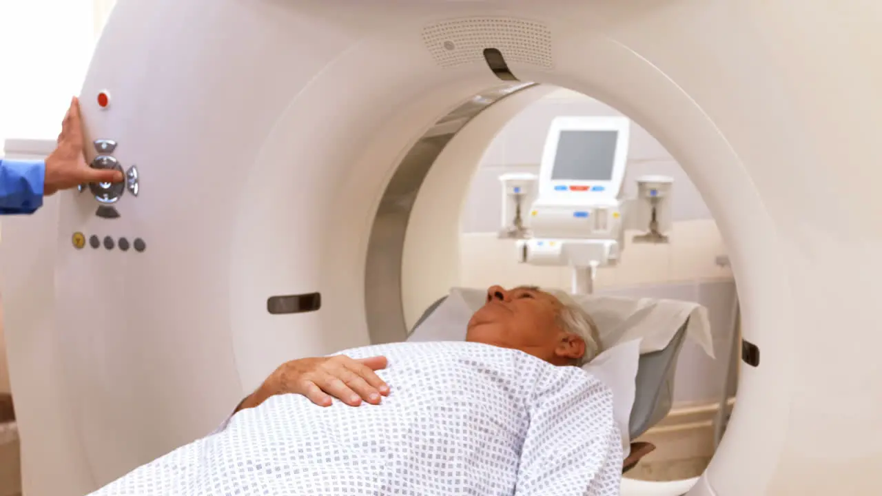 A patient is loaded into an mri machine while doctor and nurse watching