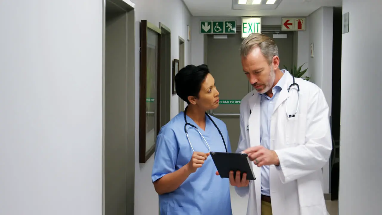 Male doctor and colleague discussing over digital tablet