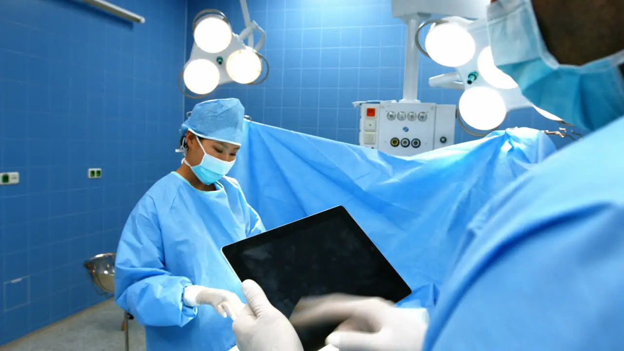 Surgeon using digital tablet while coworker operating patient in operation room