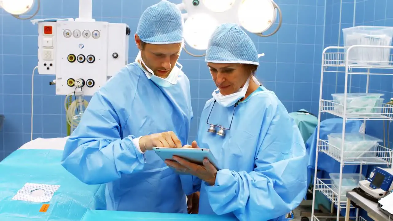 Male and female surgeons using digital tablet in operation room