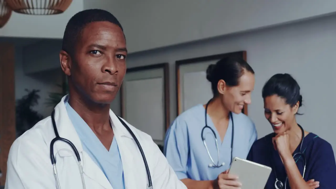 Front view of African american doctor with arm crossed looking at camera at lobby in hospital 4k