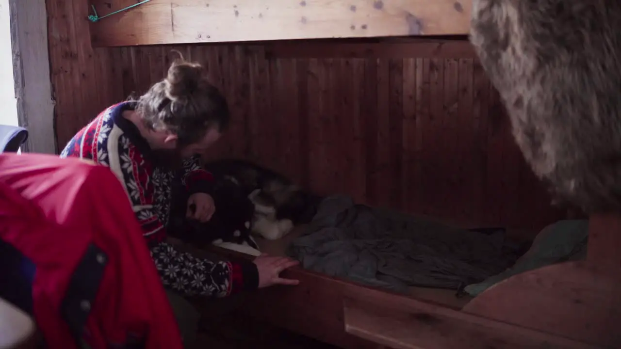 Man Touching His Pet Dog Lying Inside The Wooden Cabin