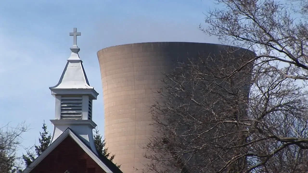 Camera Focuses On A Church Steeple And A Nuclear Power Plant In Close Proximity