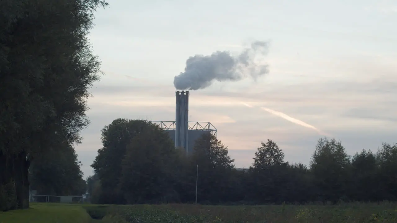 Polluting smoking factory chimney against a sunset in realtime