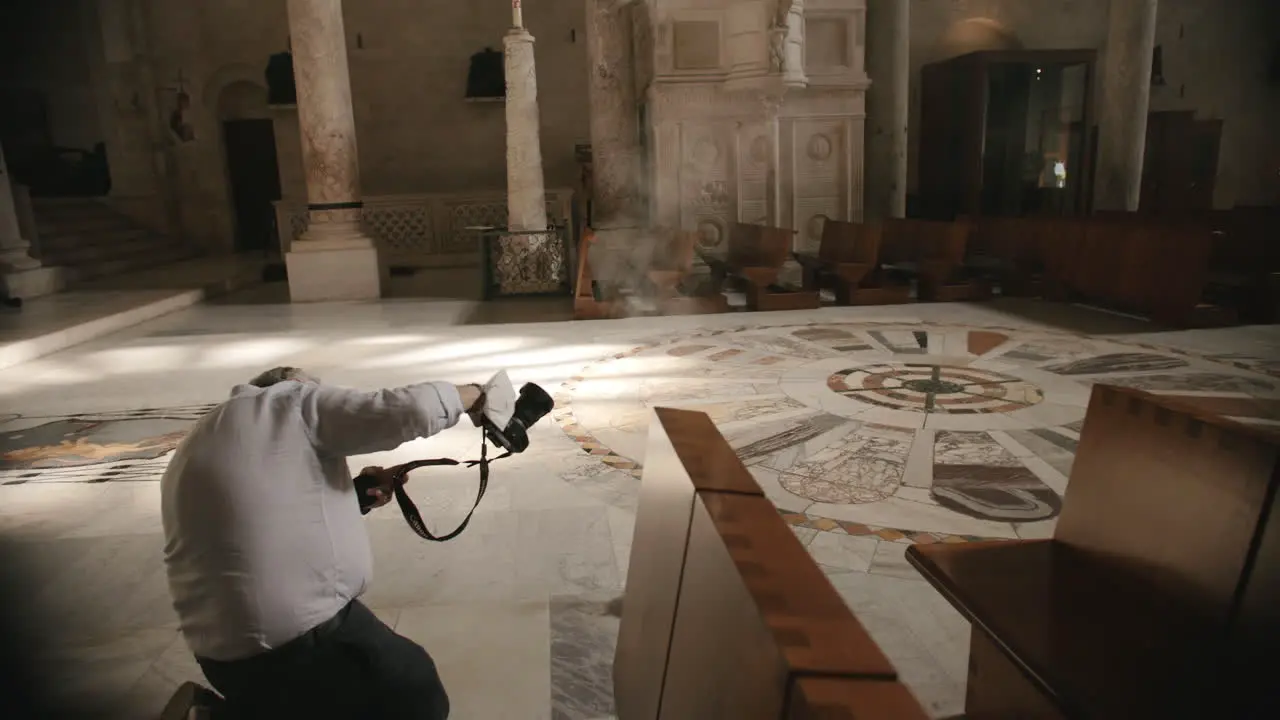 Researcher in a church in Italy taking a photograph of the sunset light shining through a window in slow motion