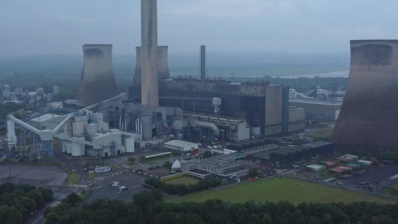 Imposing concrete cooling tower power station farmland countryside aerial view closeup zoom out