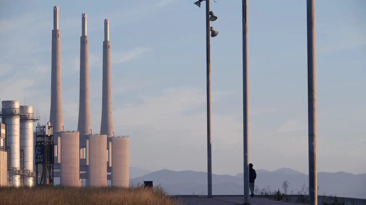 Back view of man on electric scooter and industrial chimneys in background