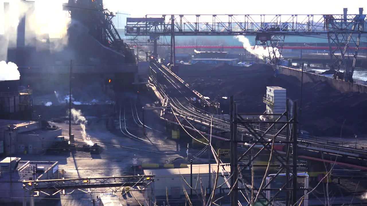 Panning shot of a busy steel mill with smoke belching suggests global warming