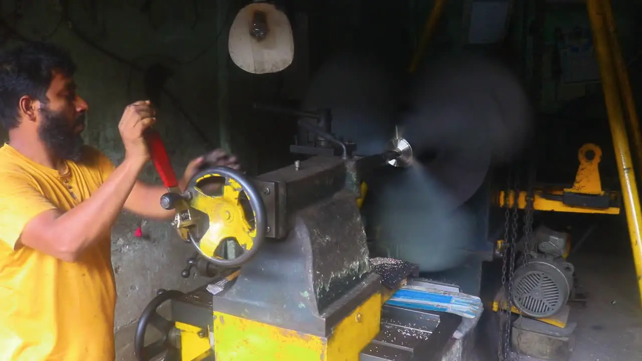 An Asian industry worker drills a hole in a ship propeller providing insight into the manufacturing process