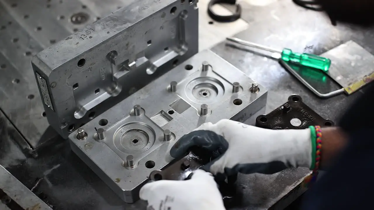 The operator is ejecting the completed part from the wax mold die in the press machine