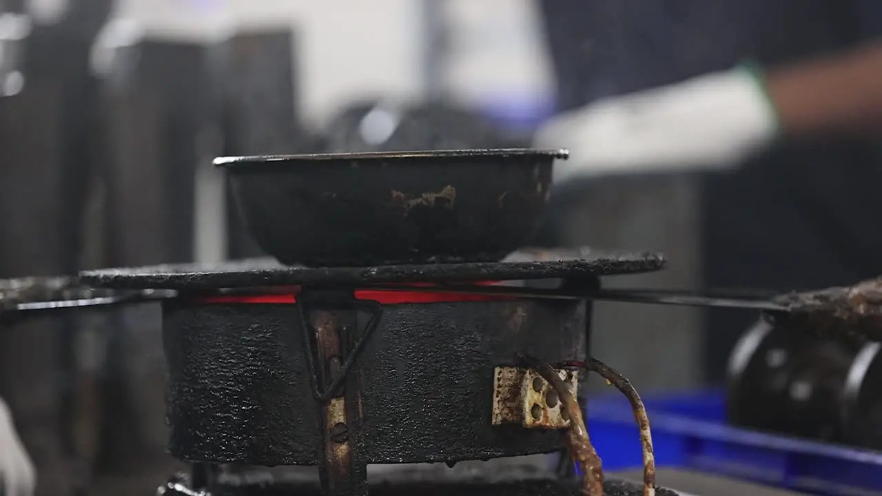 Close-up scene showing wax being heated on a court stove with smoke billowing from it