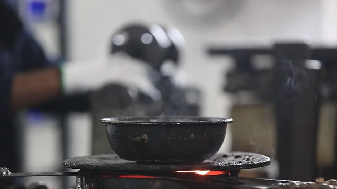 An employee wearing safety goggles attaches a wax mold to a component in an investment casting foundry