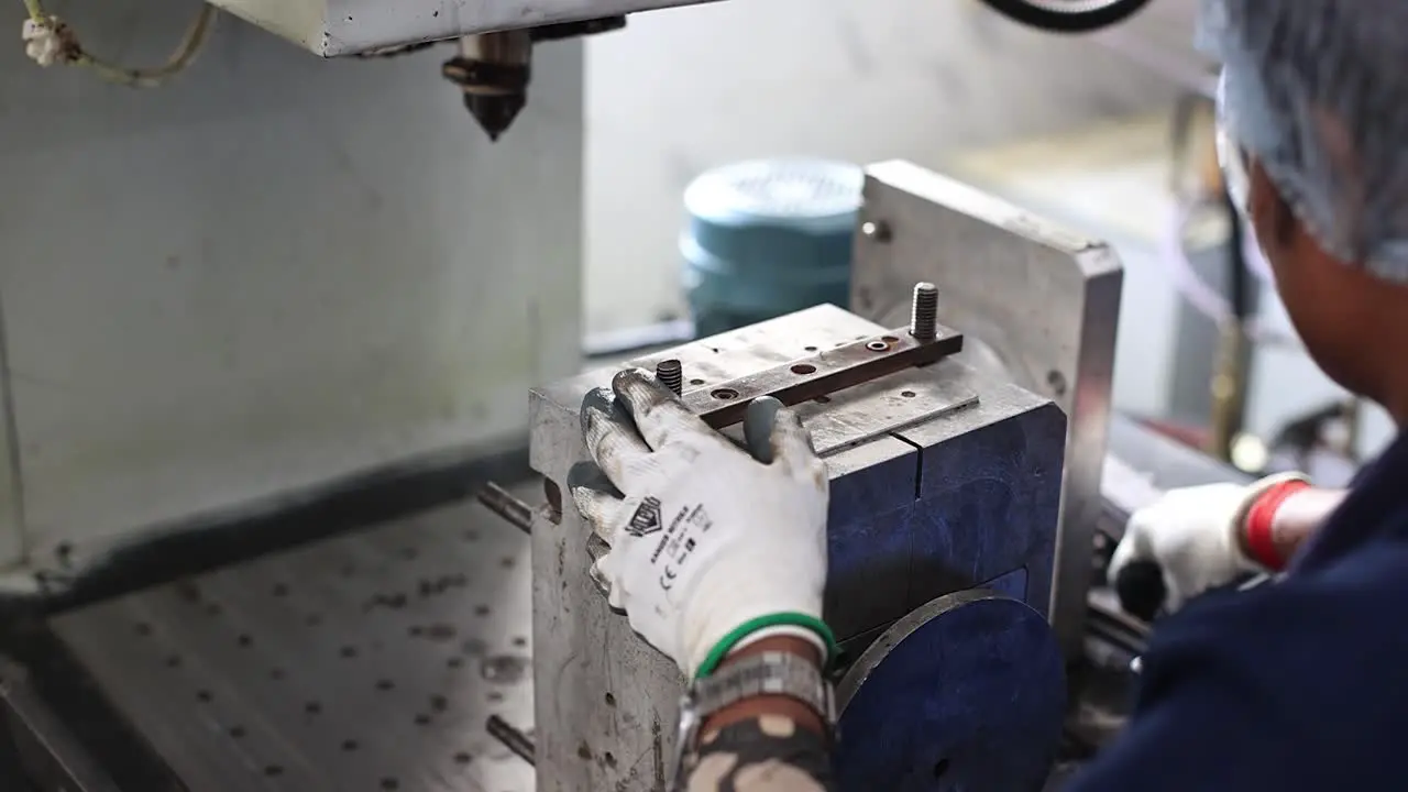 close-up scene in which an employee is closing the mold of a wax mole being prepared in an automatic machine