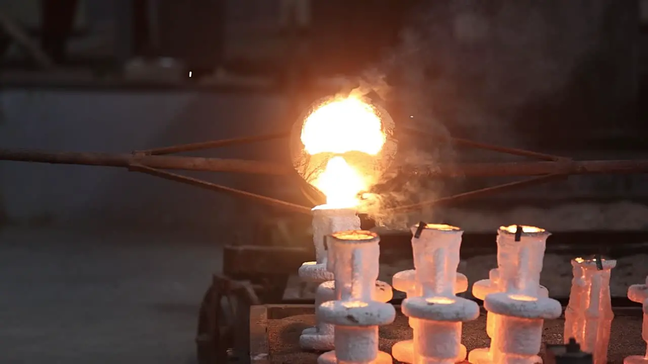 Slow motion investment casting furnace scene castings heated to high degree Celsius are being poured into sand moulds