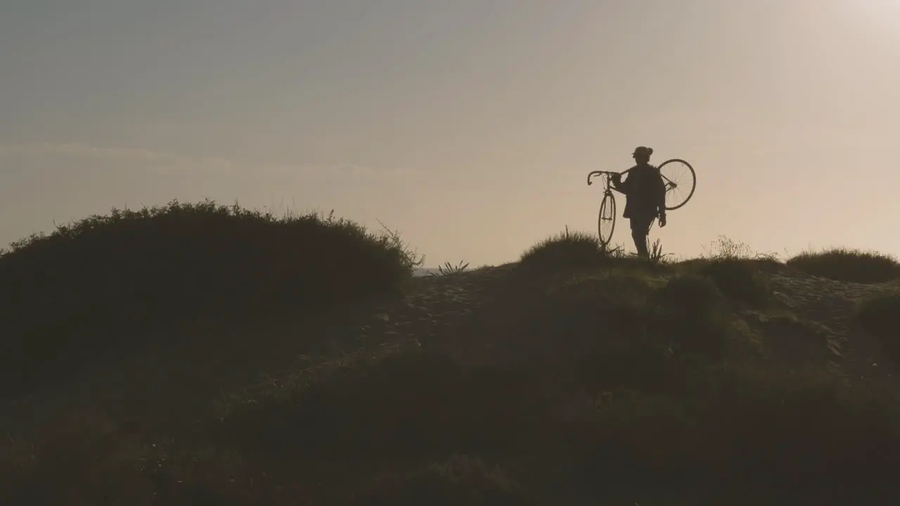 Male Carrying A Mountain Bike In The Hill Near The Beach