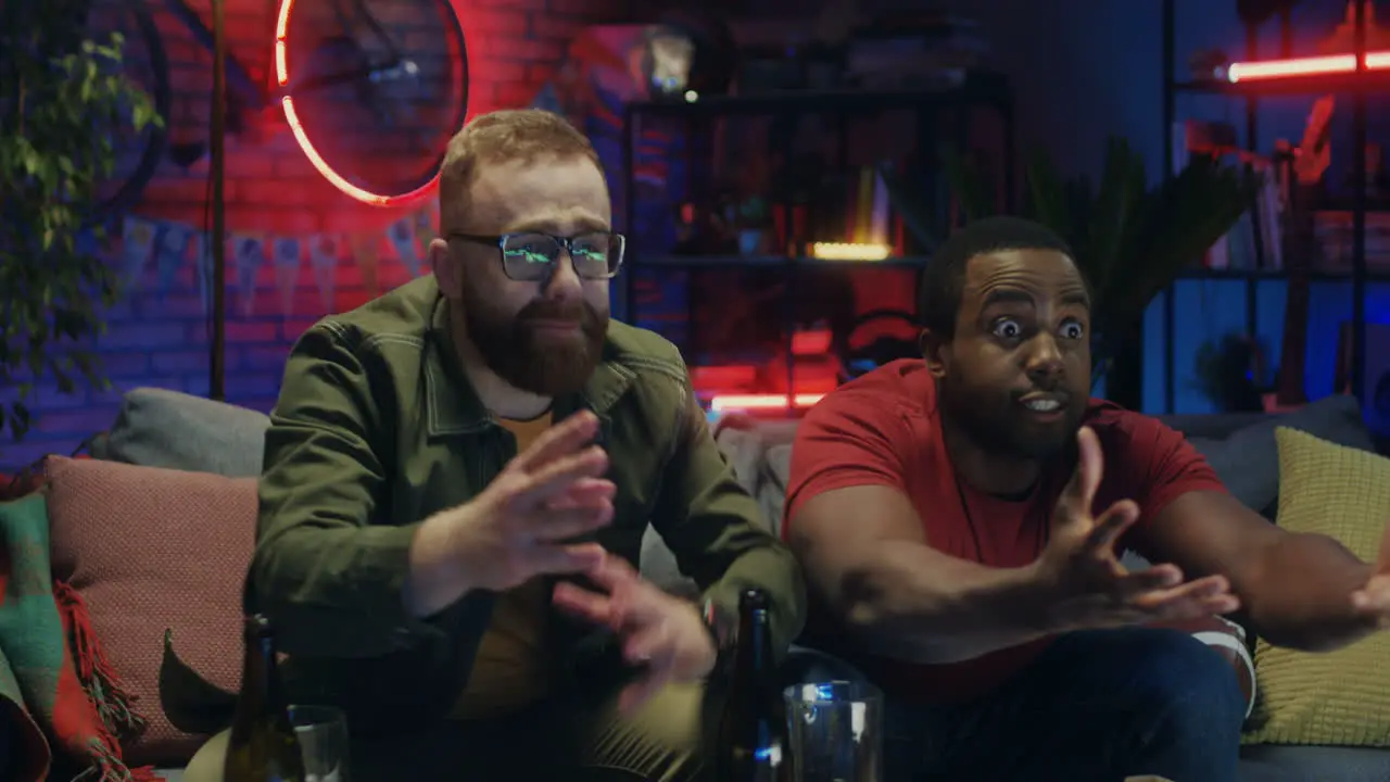 Two Mixed Races Young Men Watching Sport Match On Tv Drinking Beer And Being Upset As Their Team Lost Or Missed A Goal