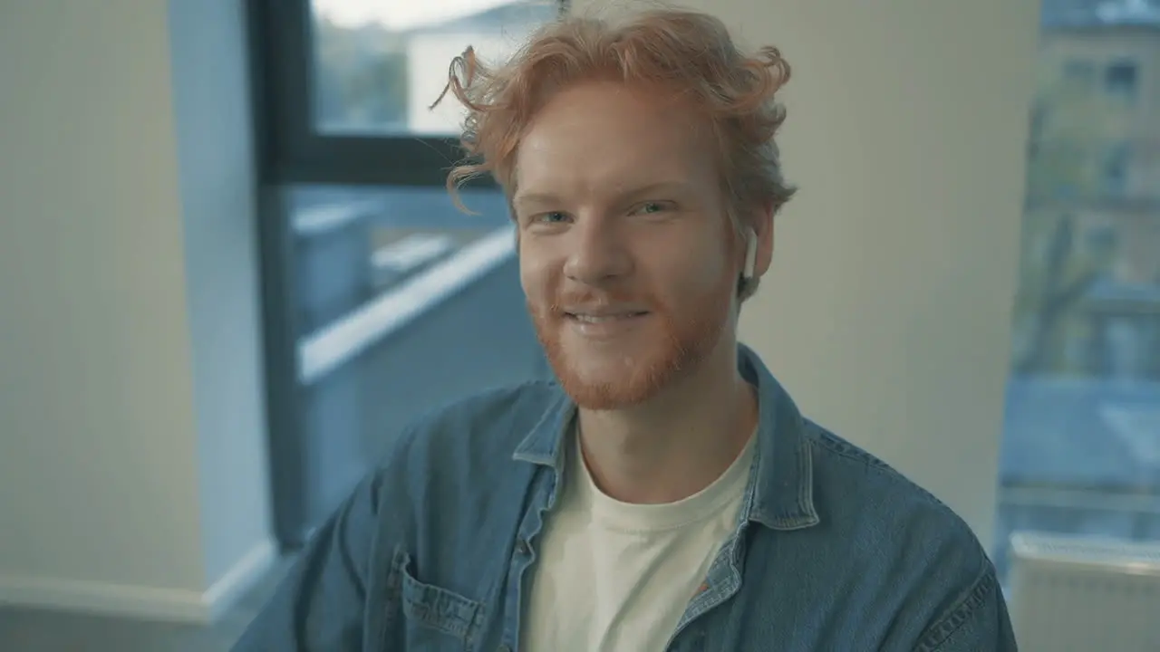 Portrait Of Young Handsome Red Haired Man Smiling And Looking At Camera Indoors