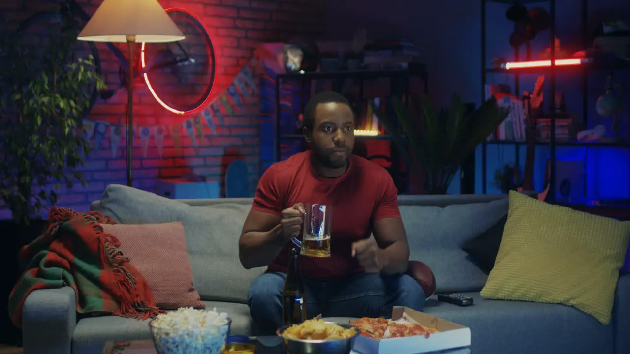 Good Looking Young Guy Drinking Beer And Cheering Up For His Favorite Team While Watching Sport Match On Tv At Night