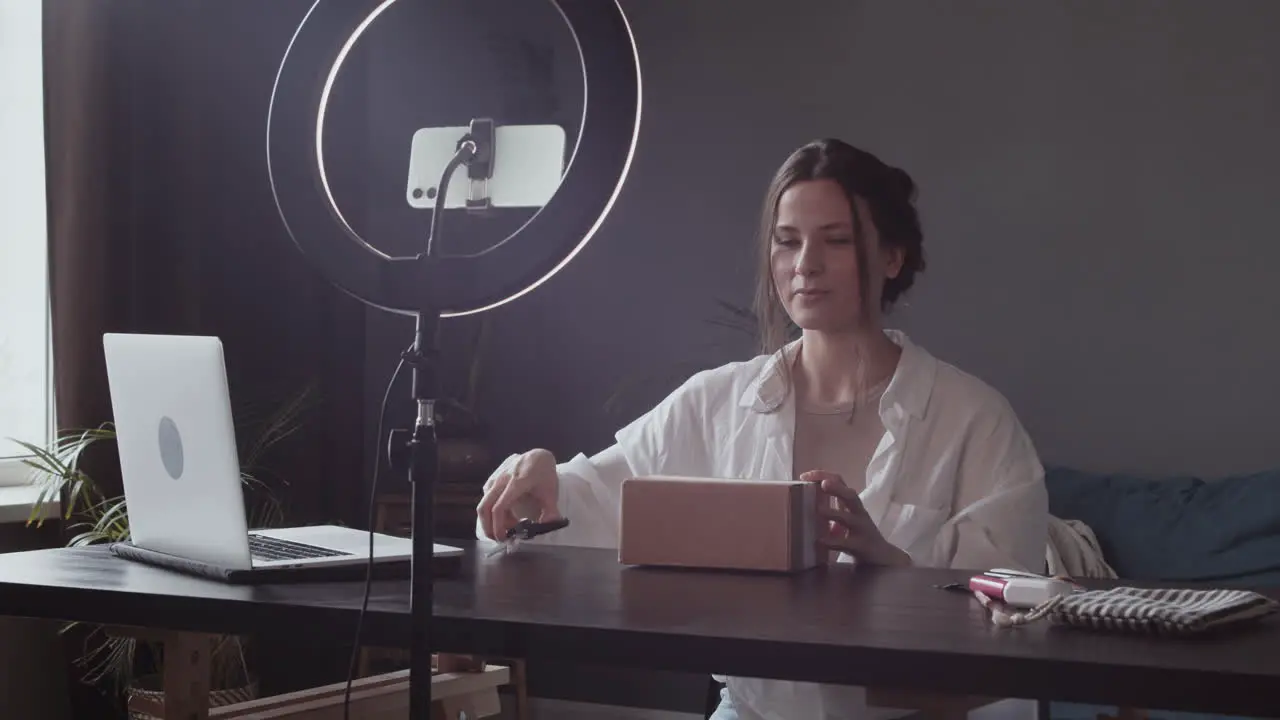 Excited Young Vlogger Woman Showing To The Camera The Package She Has Received And Opening The Box With Scissors