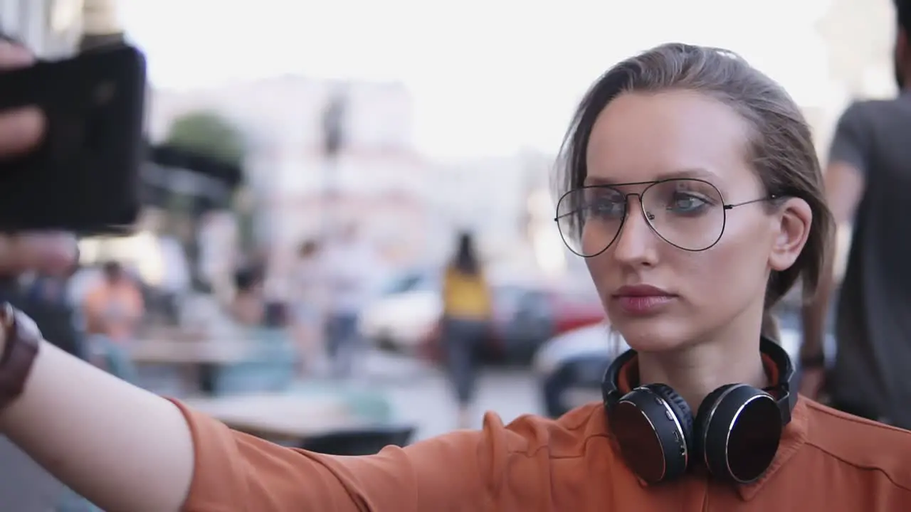 Young Woman With Light Day Make Up Standing On The Street And Taking Selfie With Her Smartphone