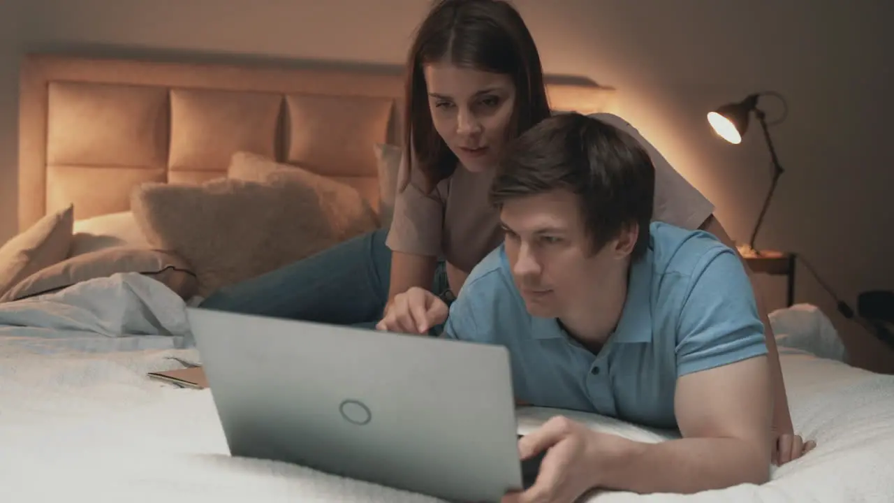 Young Couple Using Laptop On Bed Woman And Man Sharing Moments