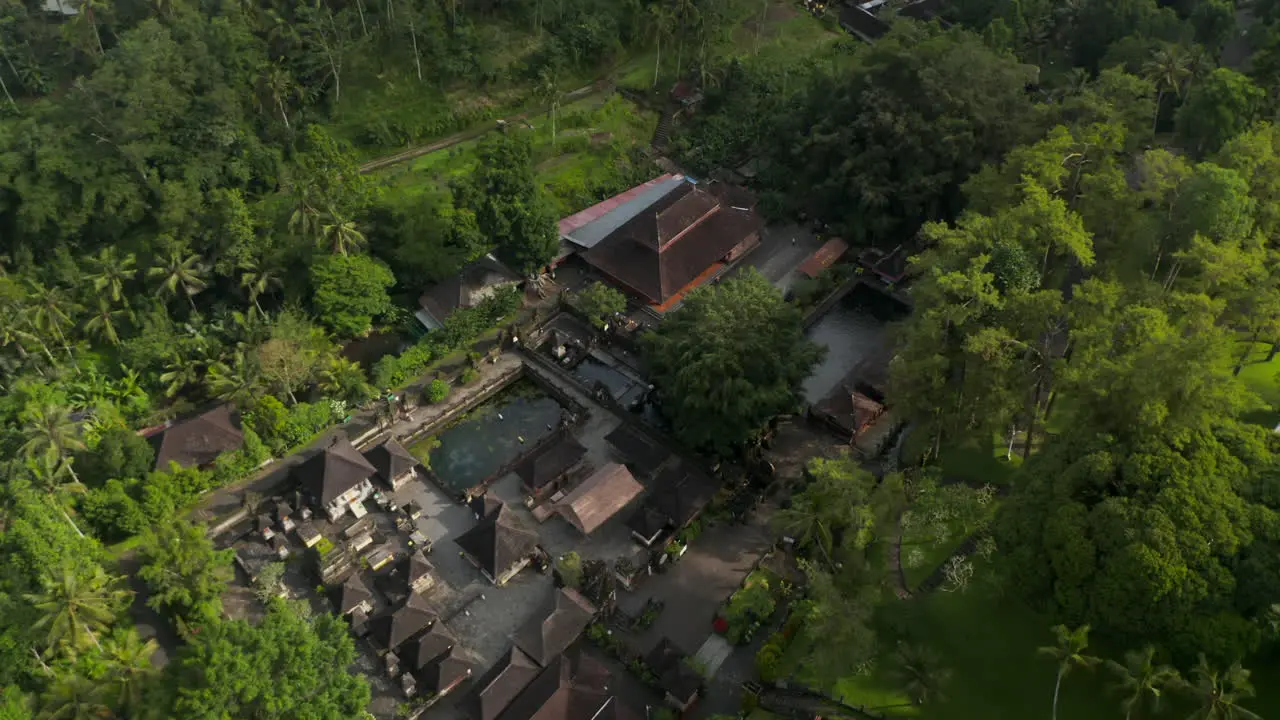 Aerial tilting into overhead view of the Hindu Balinese Tirta Empul water temple with holy spring water pond for bathing