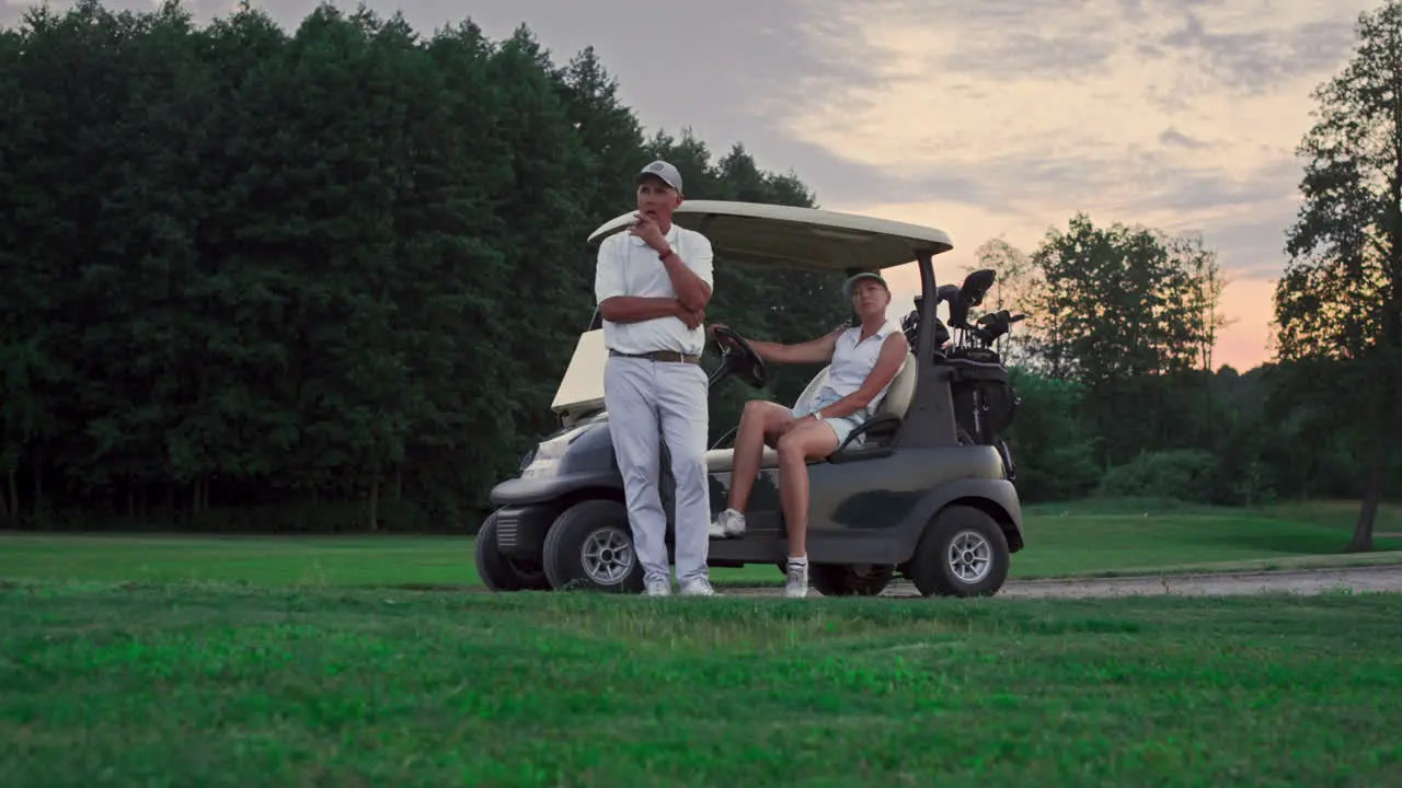 Two golfers rest outdoors on golf course Married couple relax in golf cart