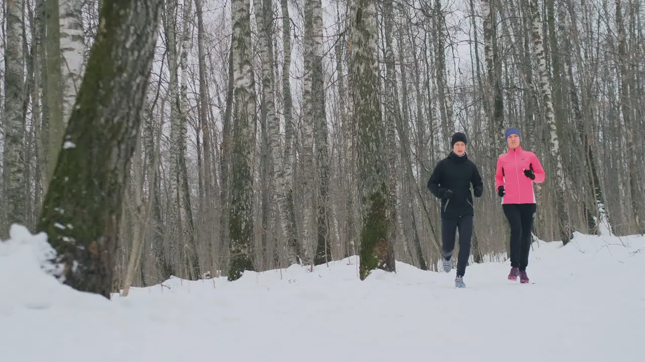 Man and woman run in the park in winter in slow motion