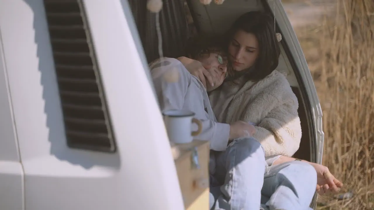 A Young Couple In Love Embracing In The Back Of A Caravan By A Lake