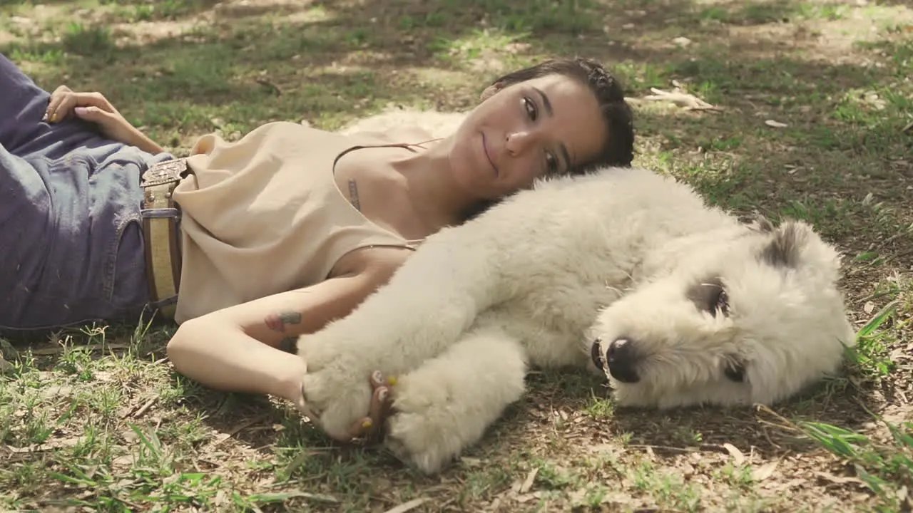 Young Woman Pets A Big Dog Lying On The Grass