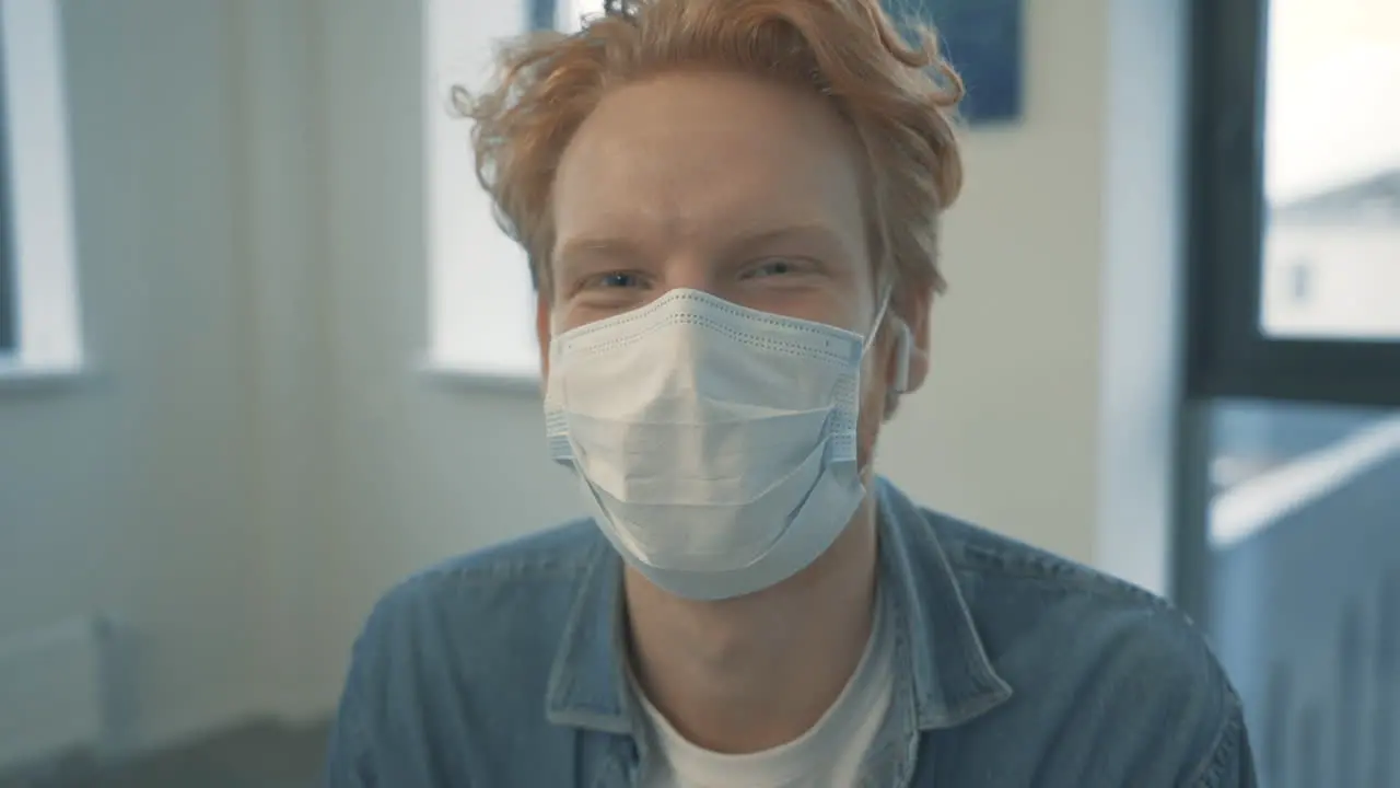 Portrait Of Young Handsome Redhead Male With Face Mask Looking At Camera And Smiling Indoor