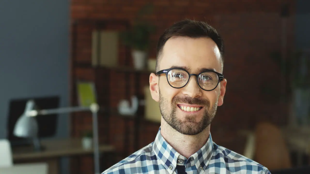 Close Of The Young Man In Glasses Turning His Head To The Camera And Smiling Cheerfully