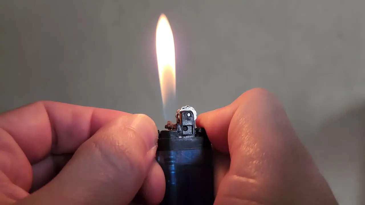 4k Video of hands holding a blue lighter and adjusting the flame with the fingers by sliding the lever which controls the butane gas levels