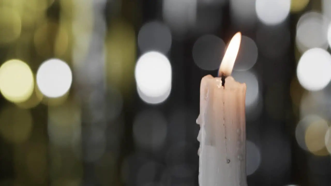 Video of white candle with white flame and copy space with bokeh on black background