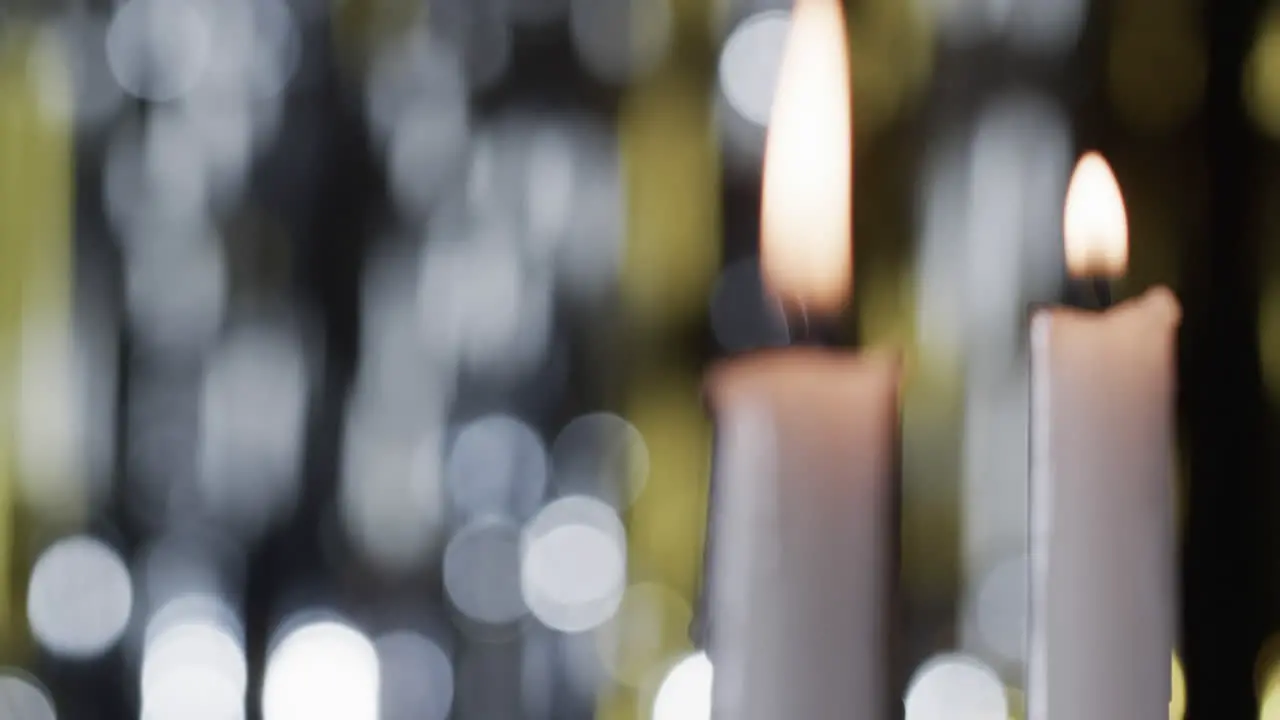 Video of white candles with white flame and copy space with bokeh on black background