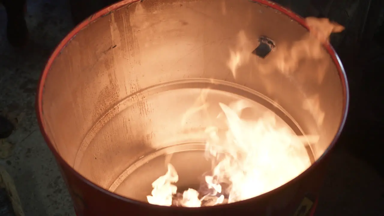 Homeless people warming near fire barrel standing at night in winter