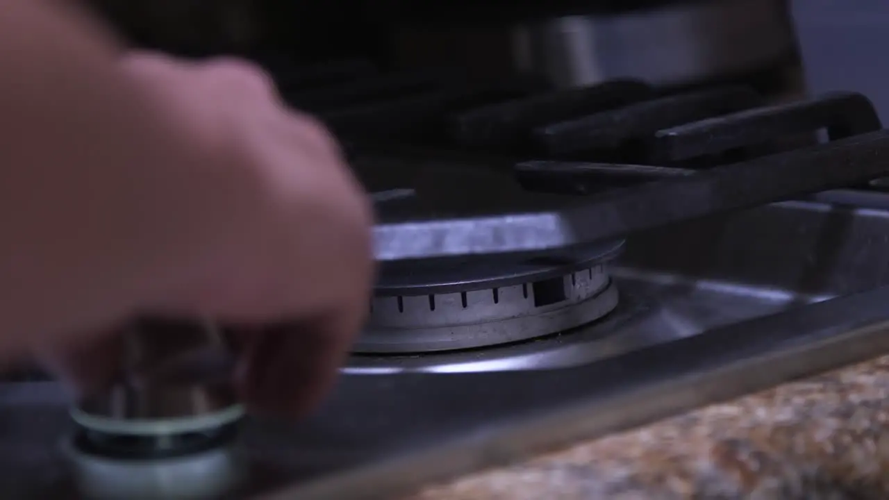 A man's hand reaches in to turn off the gas to the burner