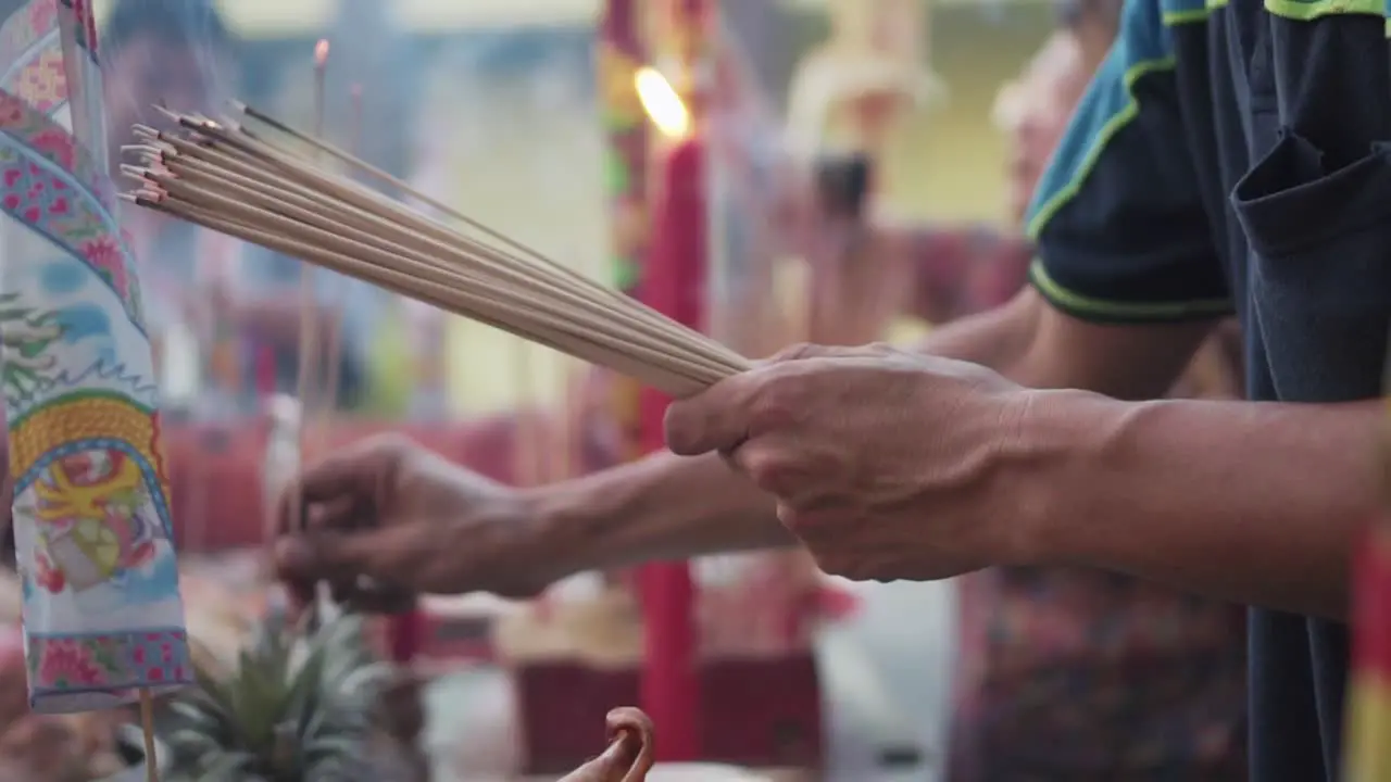 Worshiper Holding A Bunch Of Incense Stick And Insert Into The Incense Burner On The Offering Table