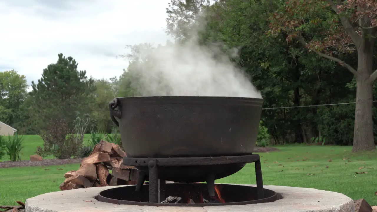 An old fashioned iron kettle over the fire of an outdoor campfire