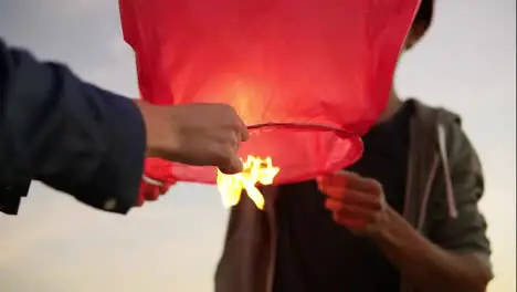 Close Up view of young multi ethnic couple holding red paper lantern before launching Attractive woman with her african boyfriend