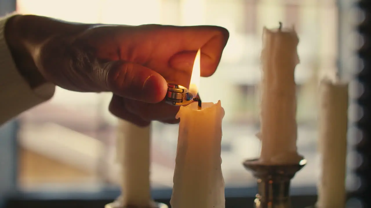 Male hand lights a candle with a lighter