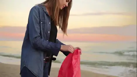 Young attractive woman holding lantern with fire before letting it fly standing by the beach together with her friends Friends