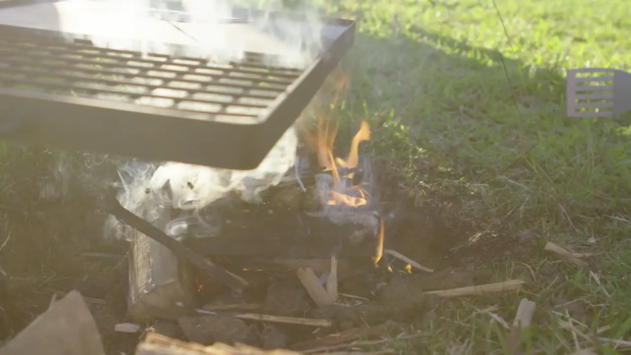 Slow movement around open campfire flames and a BBQ