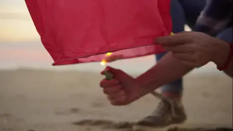 Close Up view of hands lightning before launching red paper lantern Female hands holding lantern with fire before to let it fly