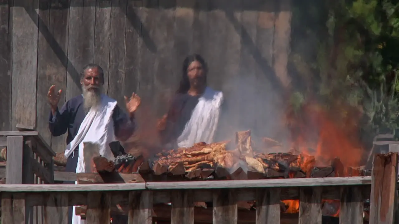 Cremation Pyre Burning With Two Priests In The Background In Iquitos