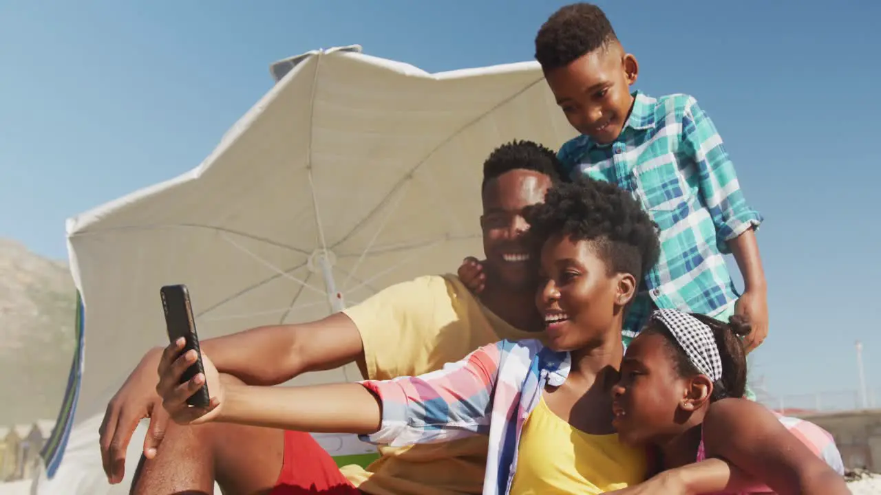 African american family taking a selfie while sitting on the beach