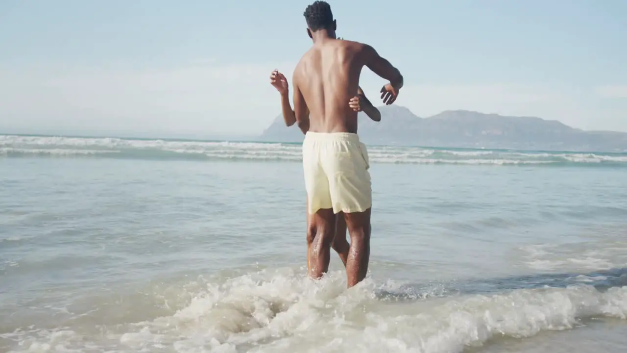 African american couple hugging each other near the waves on the beach