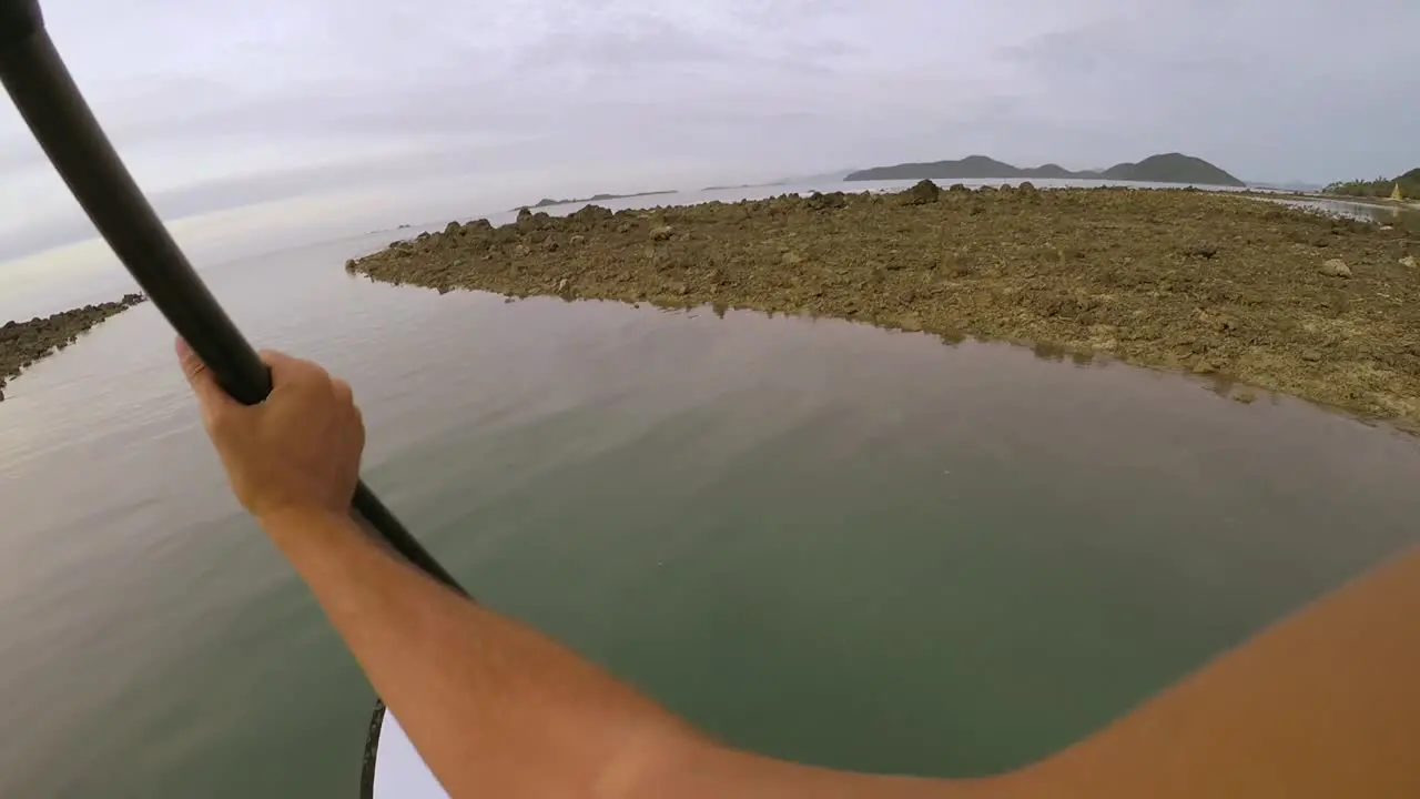 POV footage of a paddle boarder rowing through a narrow stream during sunset in Koh Samui